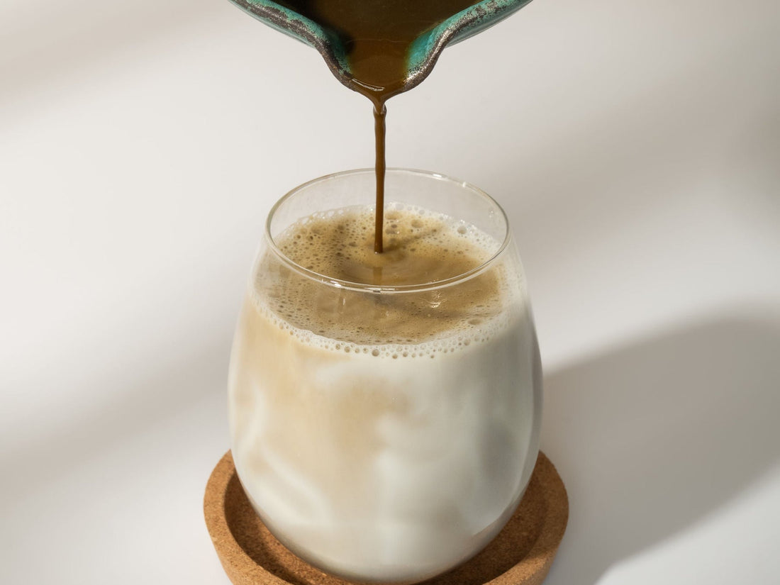 Hojicha poured from a bowl into a glass of frothed milk for a hojicha latte